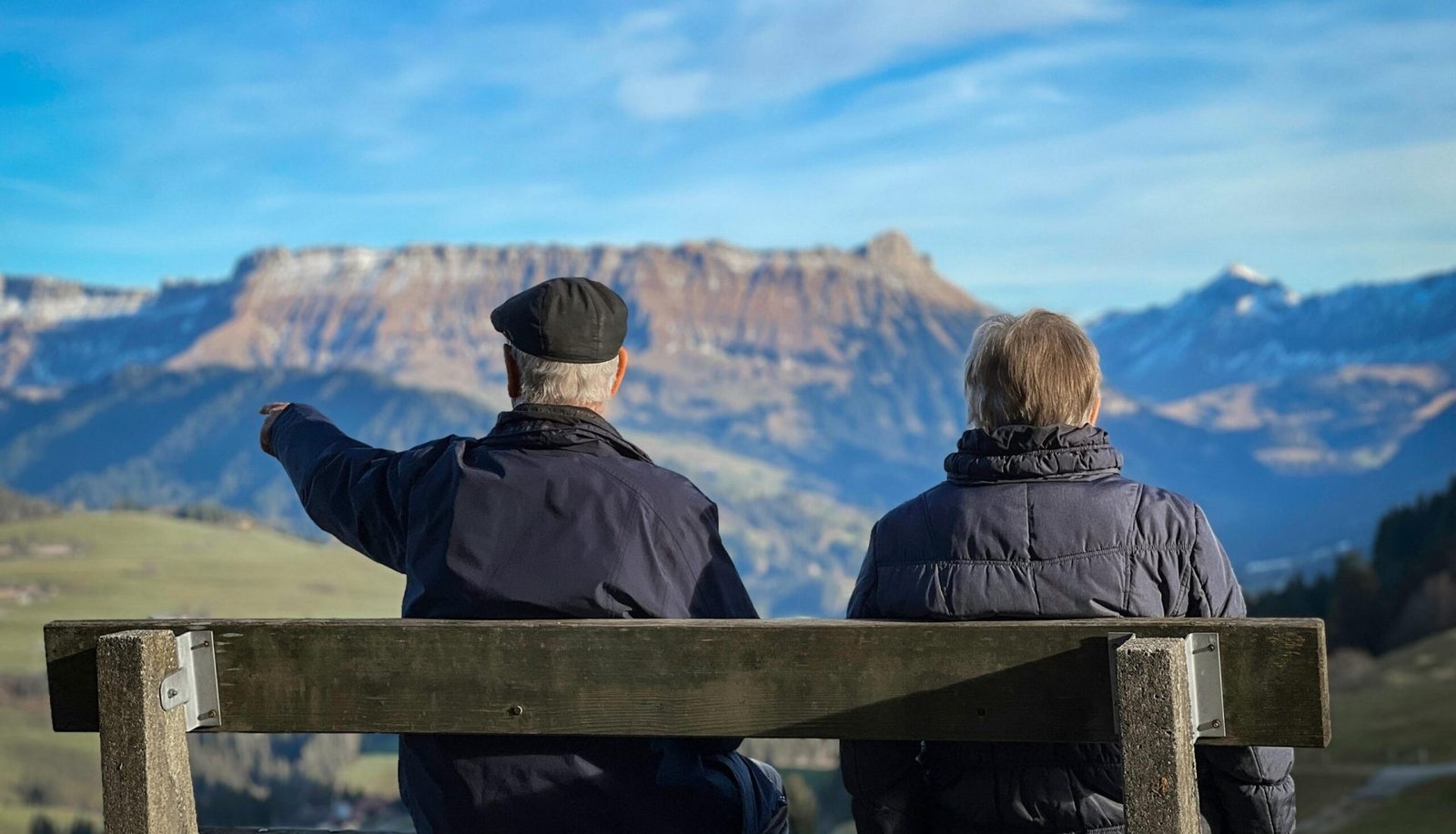Senior couple sits on bench admiring Swiss Alps landscape in Lucerne.